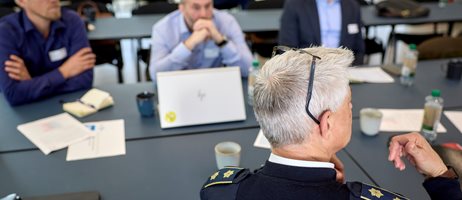 2026 05 07 Deltagere Sidder Til Møde I Et Mødelokale, Mens En Uniformeret Deltager Fra Beredskabsmyndighed Deltager I Diskussionen Recilienscenter Danmark